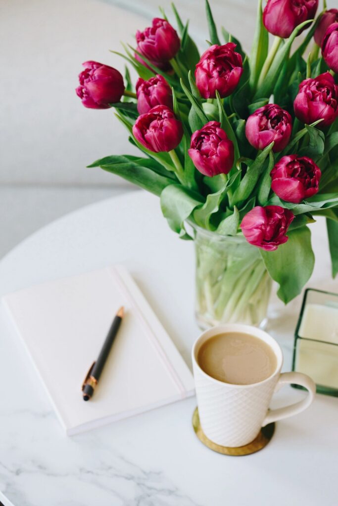 Relaxing purple tulips, coffee mug, notebook, and pen on marble table