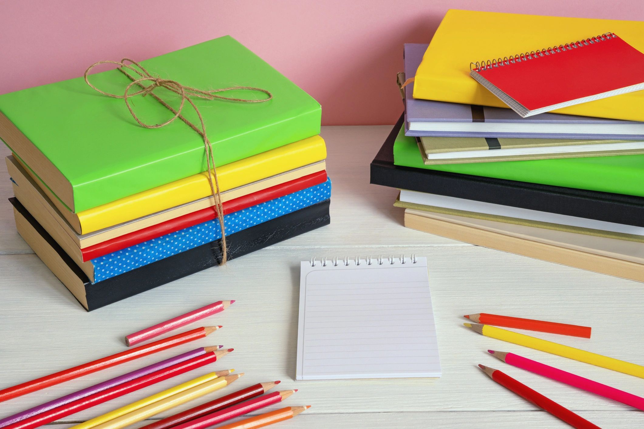 Colorful books, notebooks, and pencils arranged on a rustic table